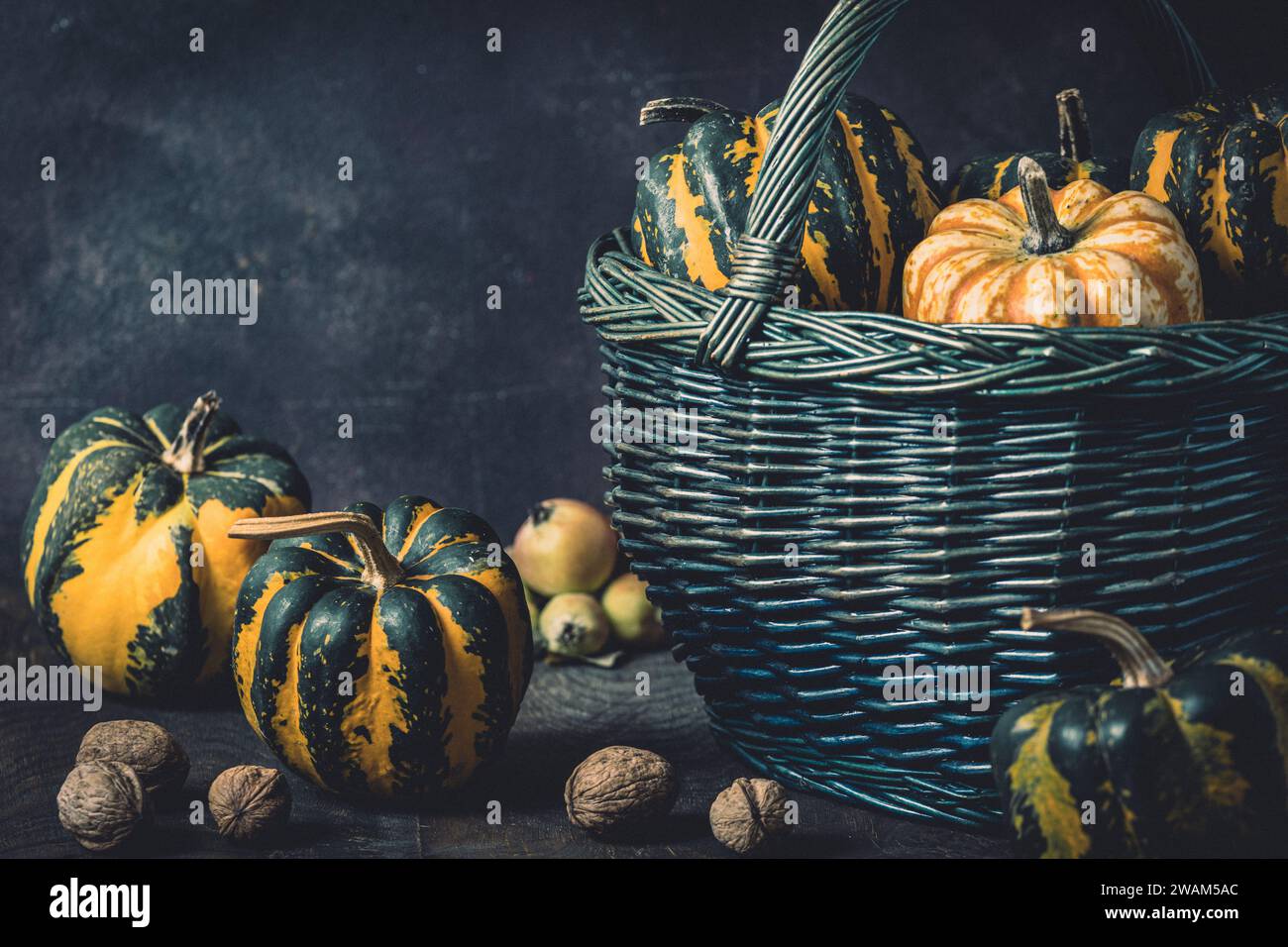 Basket with various small pumpkins with a striped pattern on dark background Stock Photo