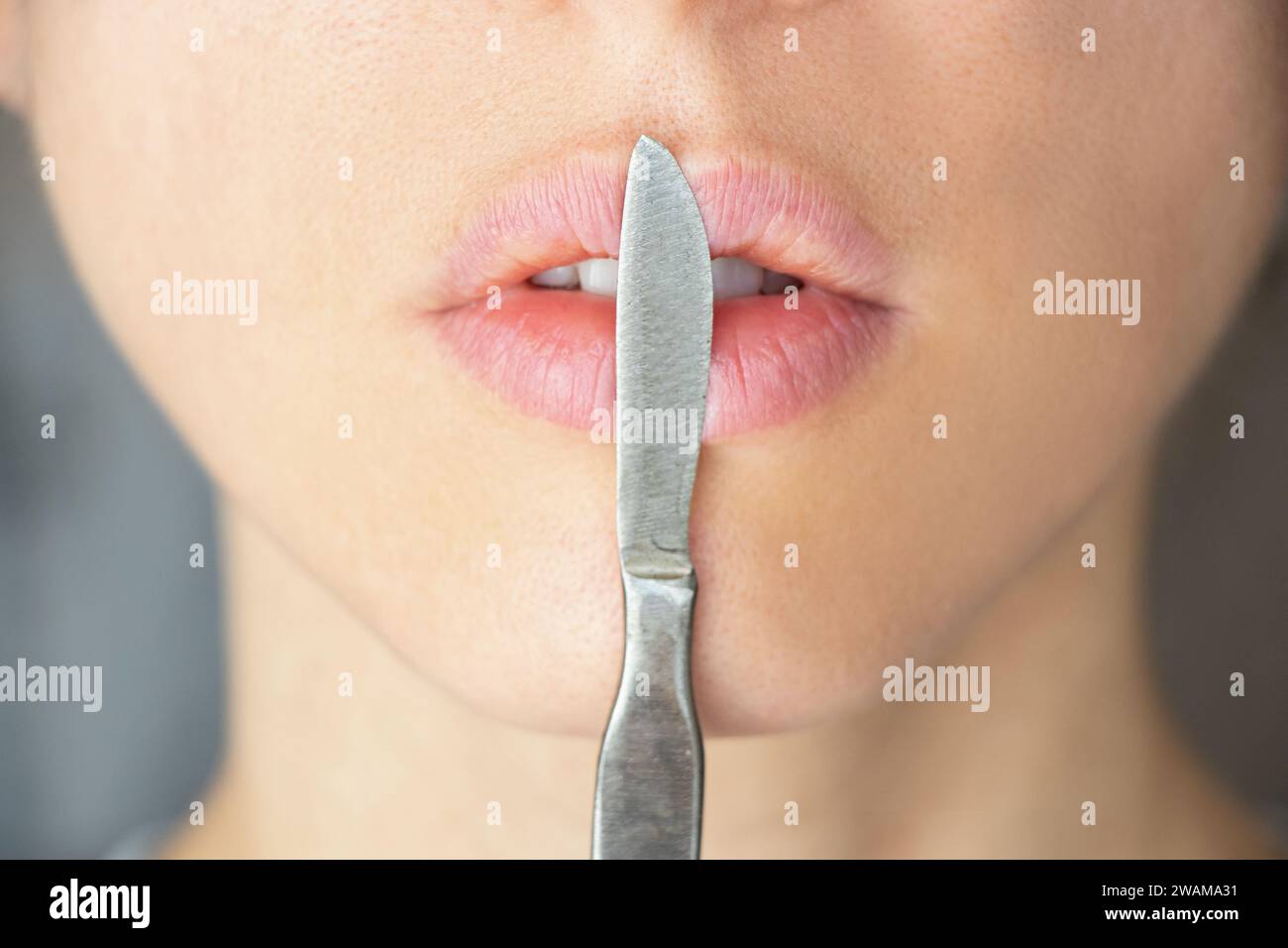 Surgical scalpel near the girl's face on the lips, beauty and fashion