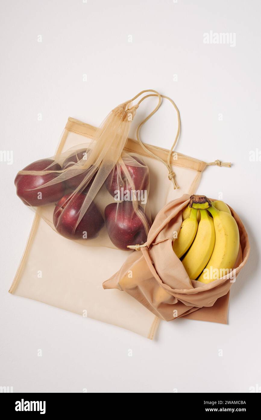 Red apples and bananas in reusable bags. Stock Photo