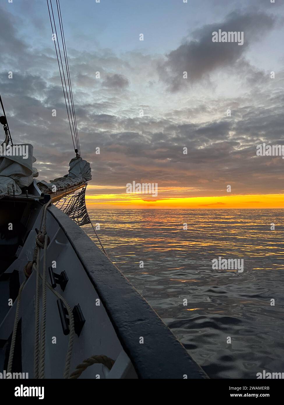 Orange sunrise over the Atlantic Ocean seen from a tall ship bow Stock Photo