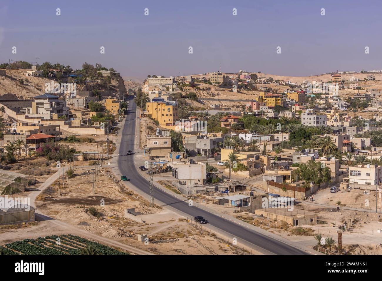 The aerial view on the road, palm tree plantation, and residential houses at Palestinian town of Jericho, West Bank, Palestine, during the hot summer Stock Photo