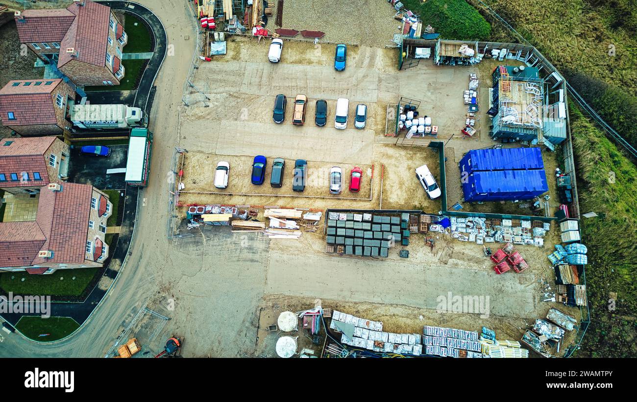 Aerial view of a construction site with materials and vehicles, surrounded by buildings. Stock Photo