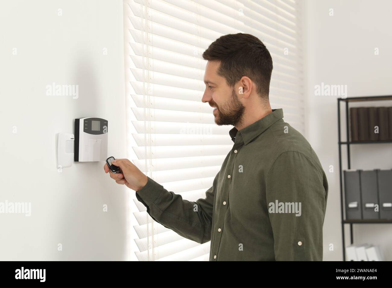 Home security system. Man using alarm key fob indoors Stock Photo