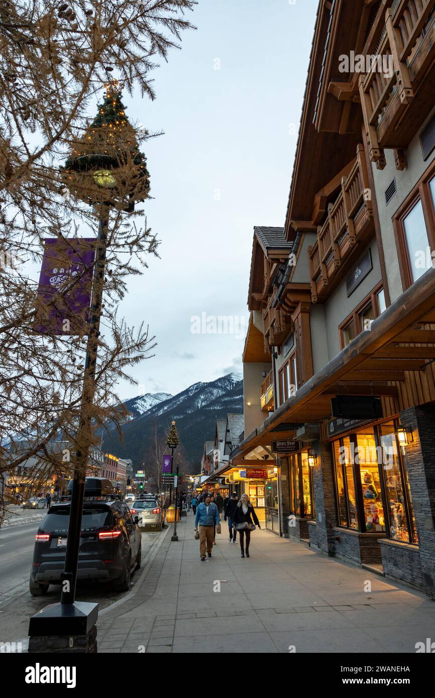Banff, Alberta, Canada.  Looking south along Banff Avenue at shops and tourists on a late winter afternoon, vertical orientation. Stock Photo