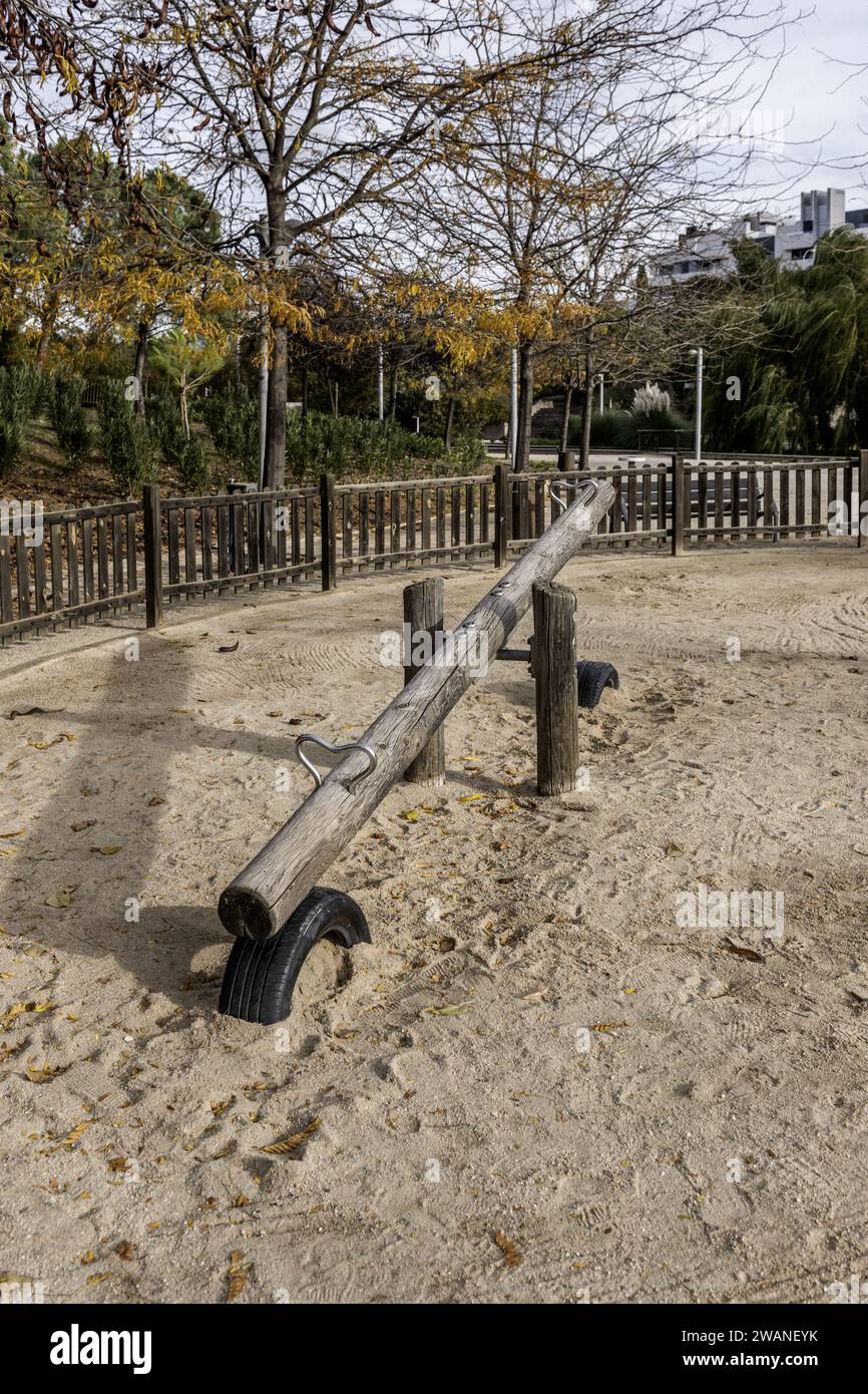 Some large untreated wooden logs with metal fittings used as playground equipment in a fenced park with sandy soils inside an urban park Stock Photo