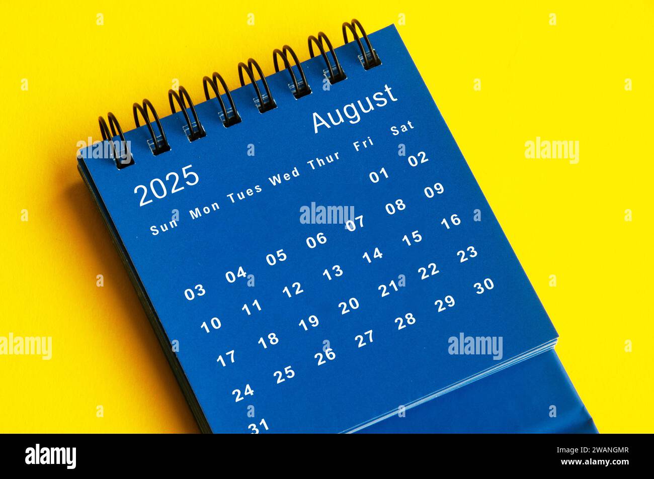 August 2025 blue desk calendar on yellow cover background. New month