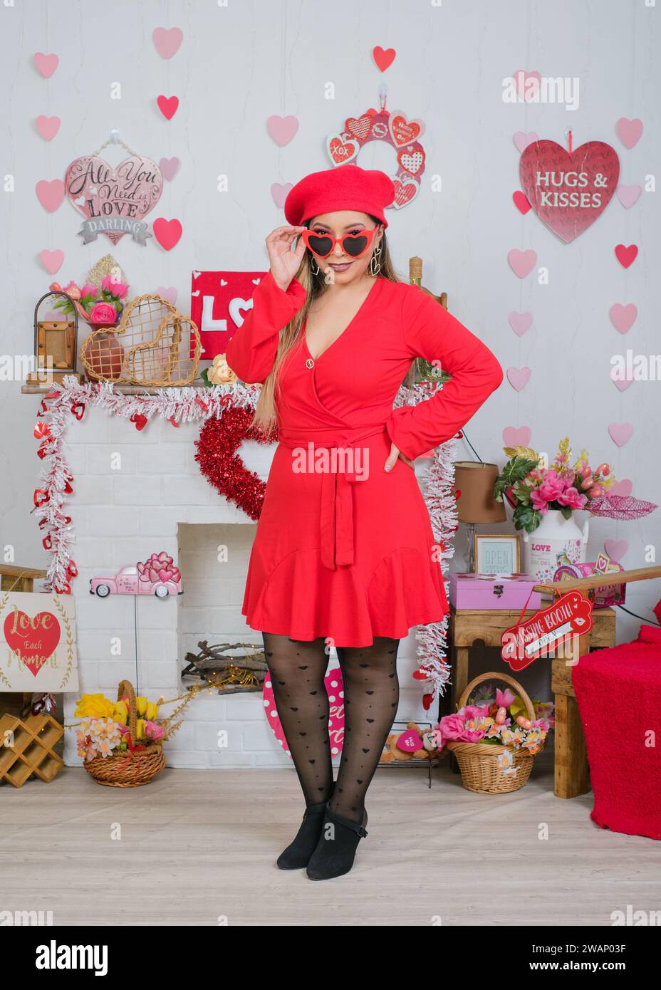 Woman wearing red dress and beret with heart shaped glasses. Decorated background for Valentine's Day. Stock Photo