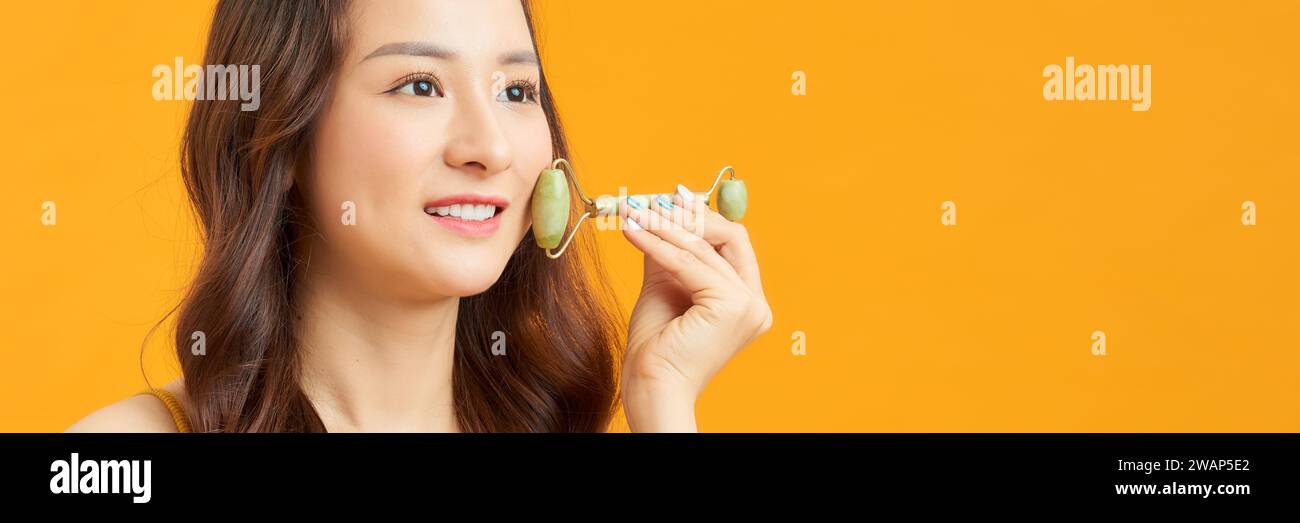 Girl using natural massager for spa treatment on yellow background Stock Photo
