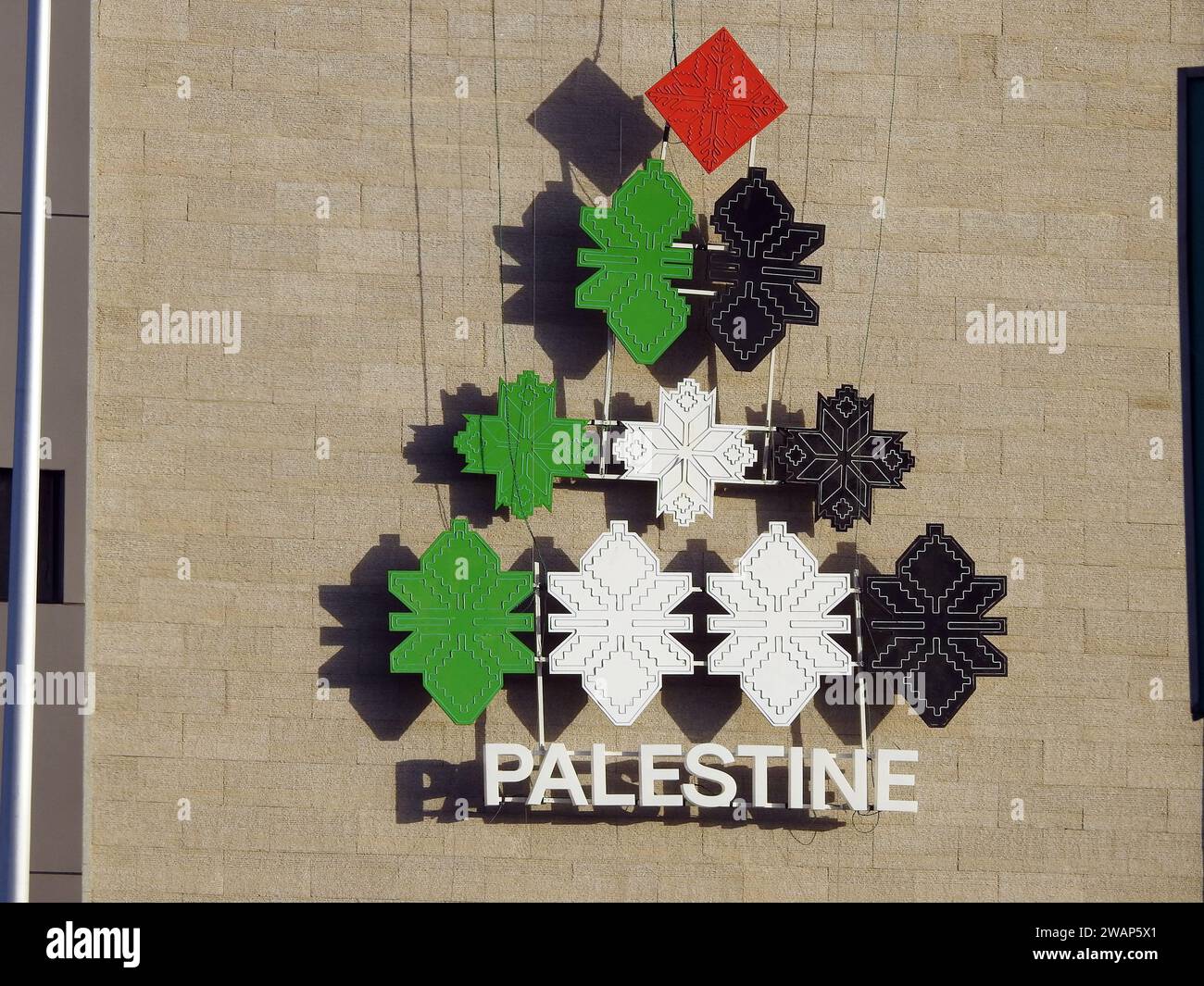 A pyramidal shape with the colors of the Palestinian flag, with the word Palestine below it, An Icon on a building in Egypt for the state of Palestine Stock Photo