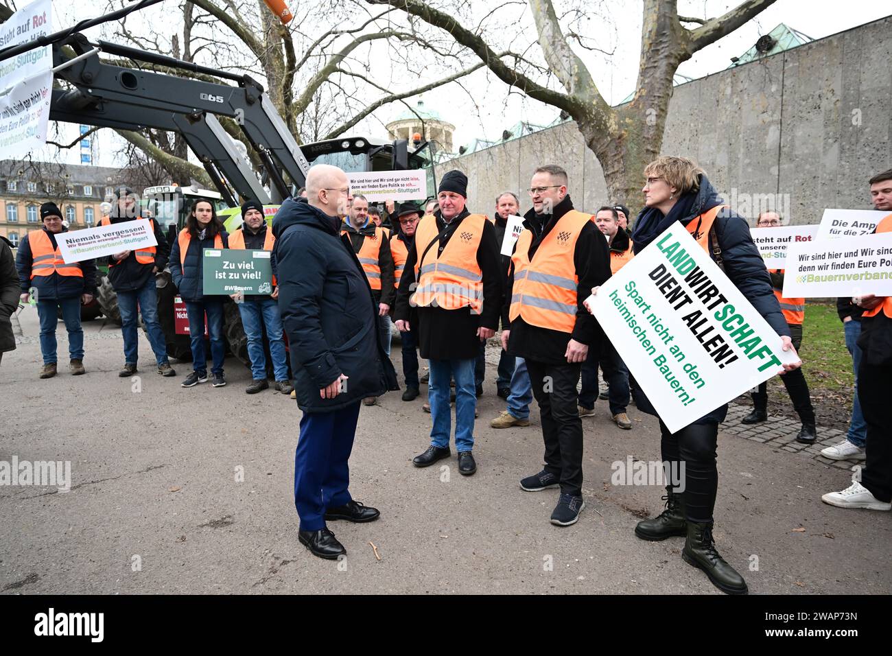 Stuttgart, Germany. 06th Jan, 2024. Michael Theurer (M), state chairman of the FDP Baden-Württemberg, talks to farmers protesting against the federal government's agricultural policy before the FDP's Epiphany meeting at the Opera House in Stuttgart. A woman holds a sign reading 'Agriculture serves everyone! Don't save on the local farmers'. The Liberals traditionally start the new year politically on January 6. Credit: Bernd Weißbrod/dpa/Alamy Live News Stock Photo