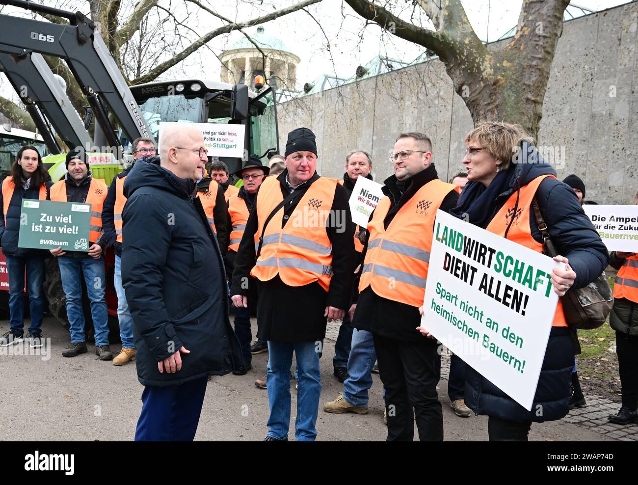 Stuttgart, Germany. 06th Jan, 2024. Michael Theurer (l), state chairman of the FDP Baden-Württemberg, talks to farmers protesting against the federal government's agricultural policy before the FDP's Epiphany meeting at the opera house in Stuttgart. A woman holds a sign reading 'Agriculture serves everyone! Don't save on the local farmers'. The Liberals traditionally start the new year politically on January 6. Credit: Bernd Weißbrod/dpa/Alamy Live News Stock Photo
