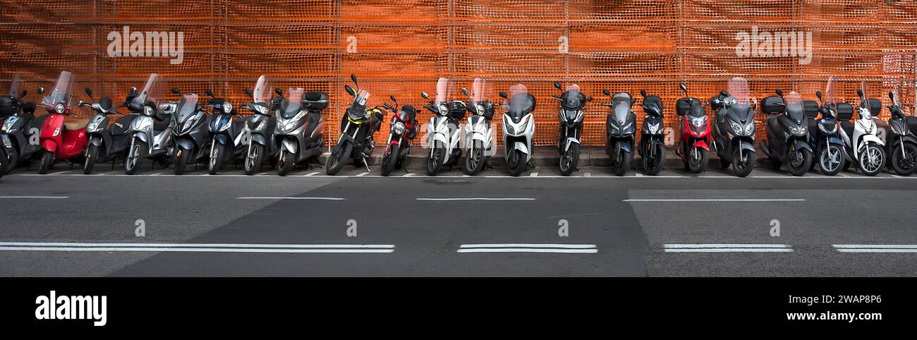 Parked scooters in front of a red scaffolding net, Genoa, Italy, Europe Stock Photo