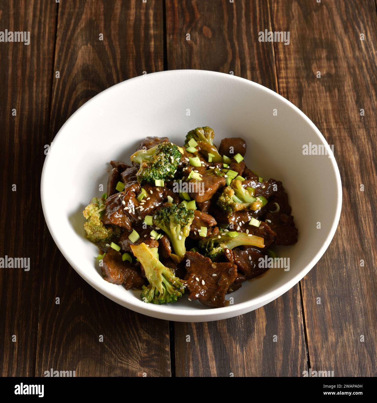 Stewed beef with broccoli in bowl over wooden background. Thinly sliced beef meat with roasted broccoli. Close up view Stock Photo