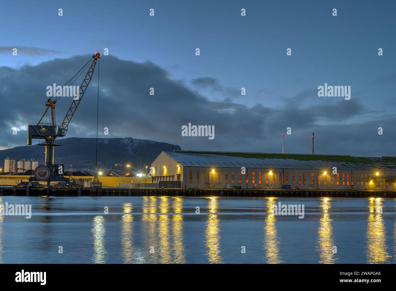 A loading crane and a storehouse in the port of Belfast at dusk Stock Photo