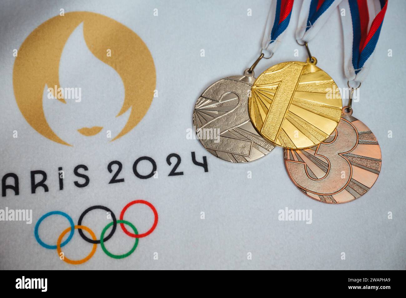 PARIS, FRANCE, JANUARY 4. 2024: Gold silver and bronze medal on white blanket with official logo of Summer olympic game in Paris 2024 Stock Photo