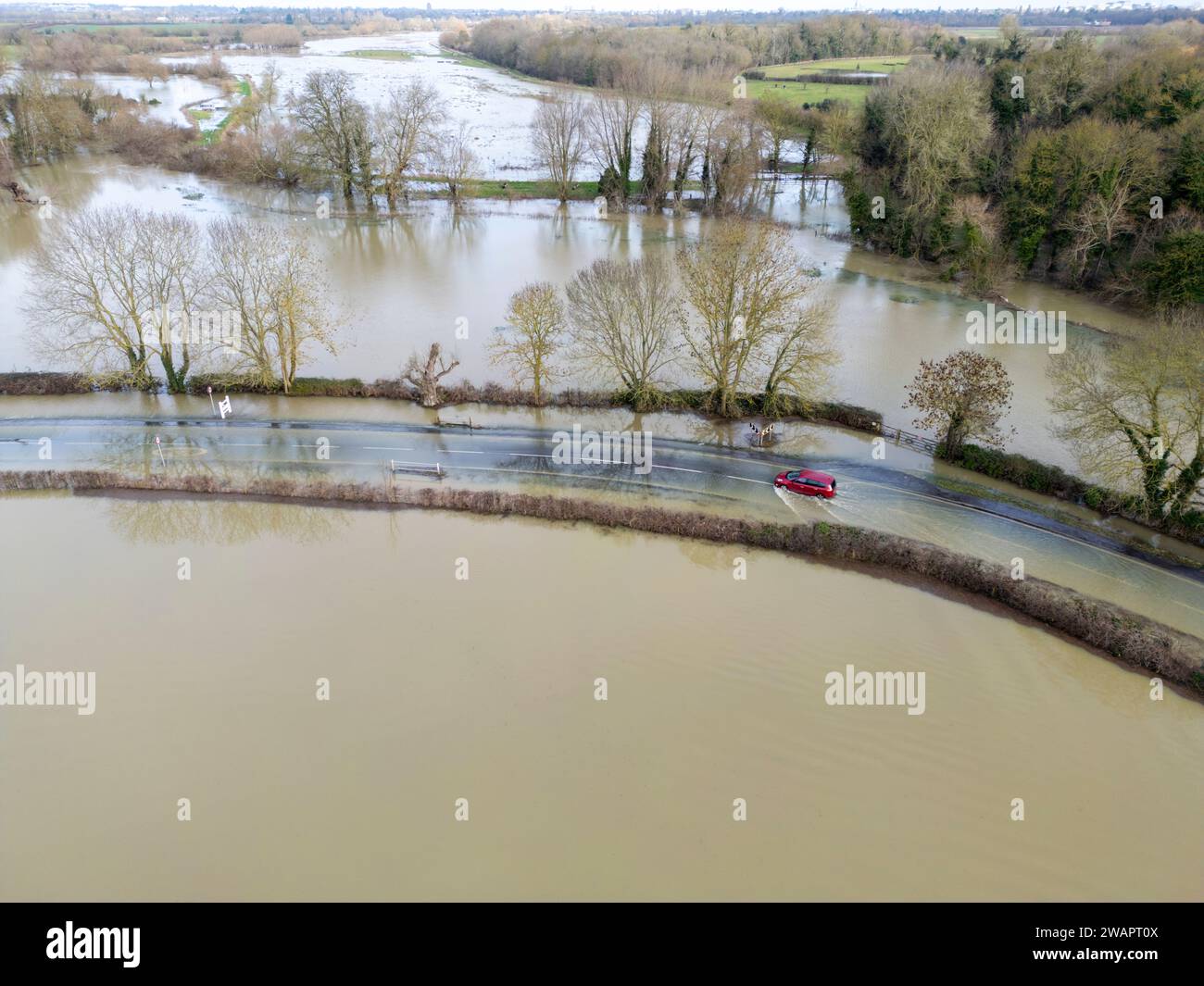 Grantchester, Cambridge, 6th January 2024. The River Cam has burst it's banks flooding the road through the village, the surrounding fields and the famous Grantchester Meadows after weeks of wet weather. Cars can still get through with care. Prolonged spells of heavy rain have caused flooding across much of the UK this winter. Credit: Julian Eales/Alamy Live News Stock Photo