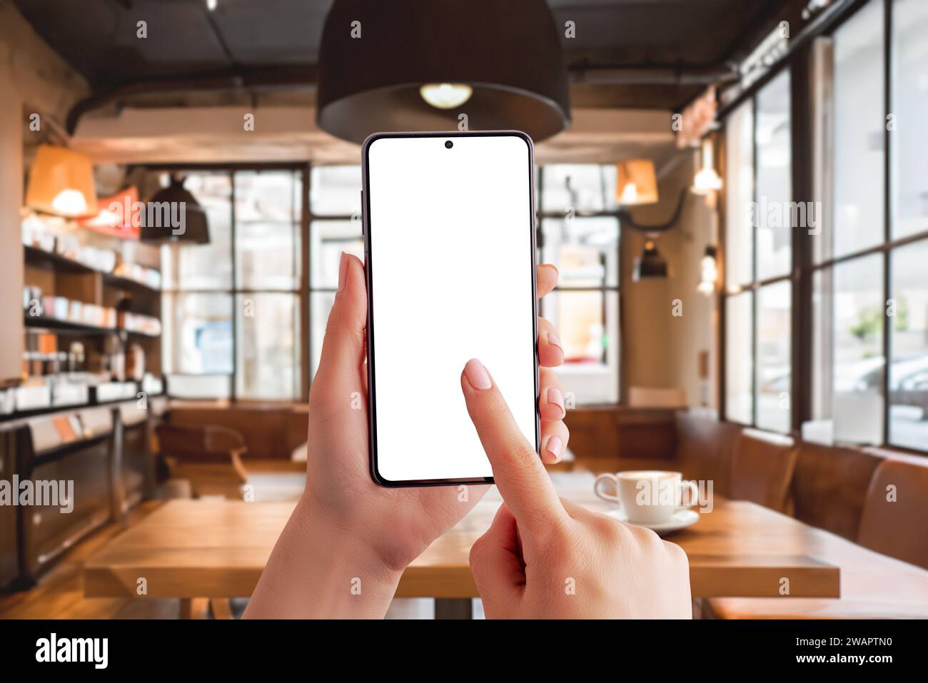 Smartphone mockup in a coffee shop, capturing the essence of a productive morning. Ideal for showcasing the work on mobile concept in a trendy cafe se Stock Photo