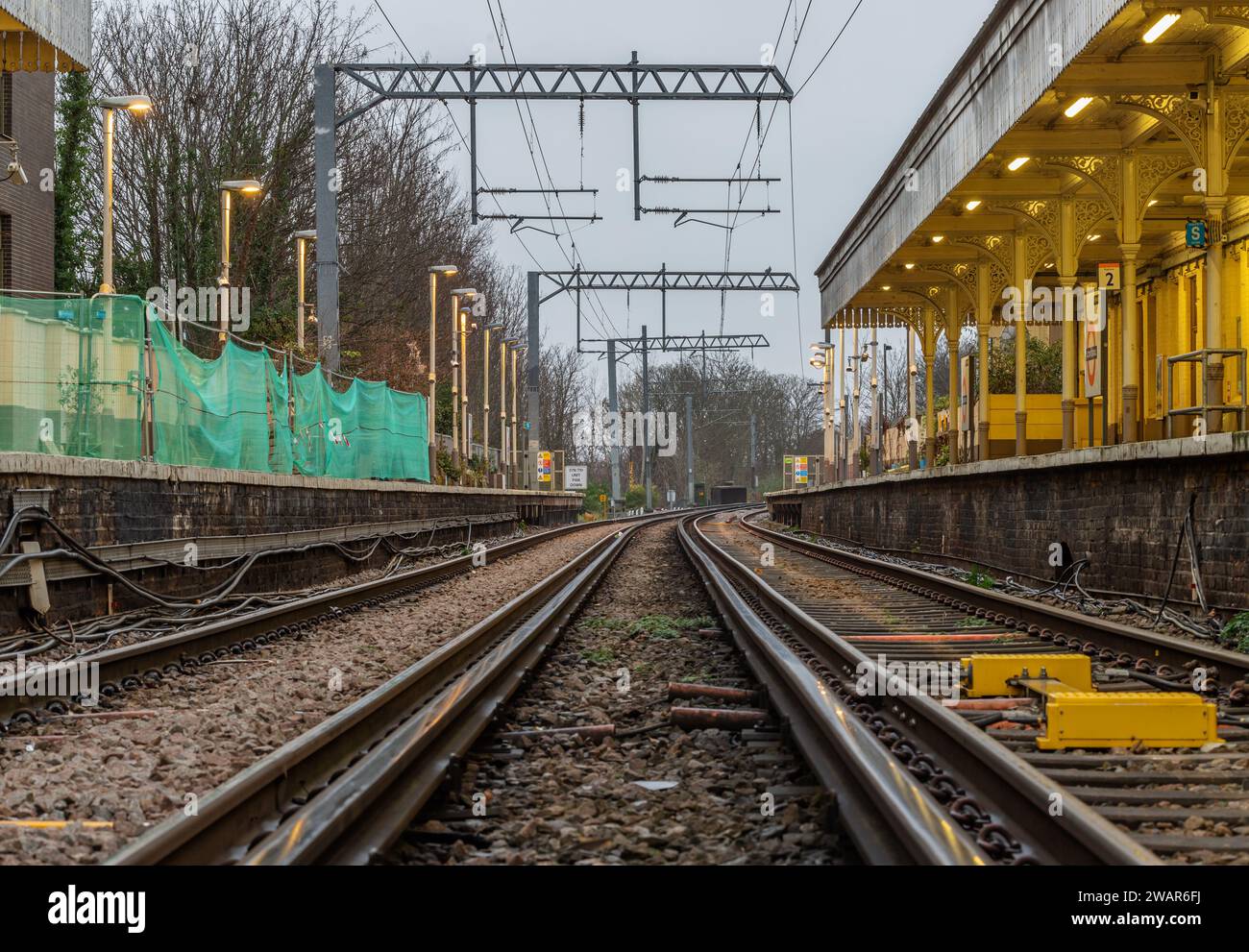 London, UK - Dec 25, 2023 - Perspective view on empty railway tracks and electric infrastructure equipment, wires at Acton central rail station. The R Stock Photo