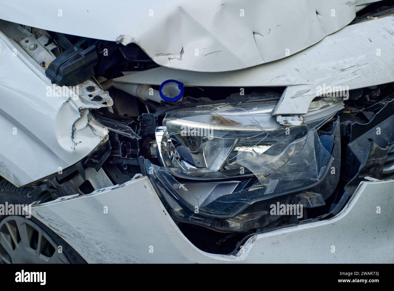 closeup of an accident damage at a headlamp and fenders of a white car
