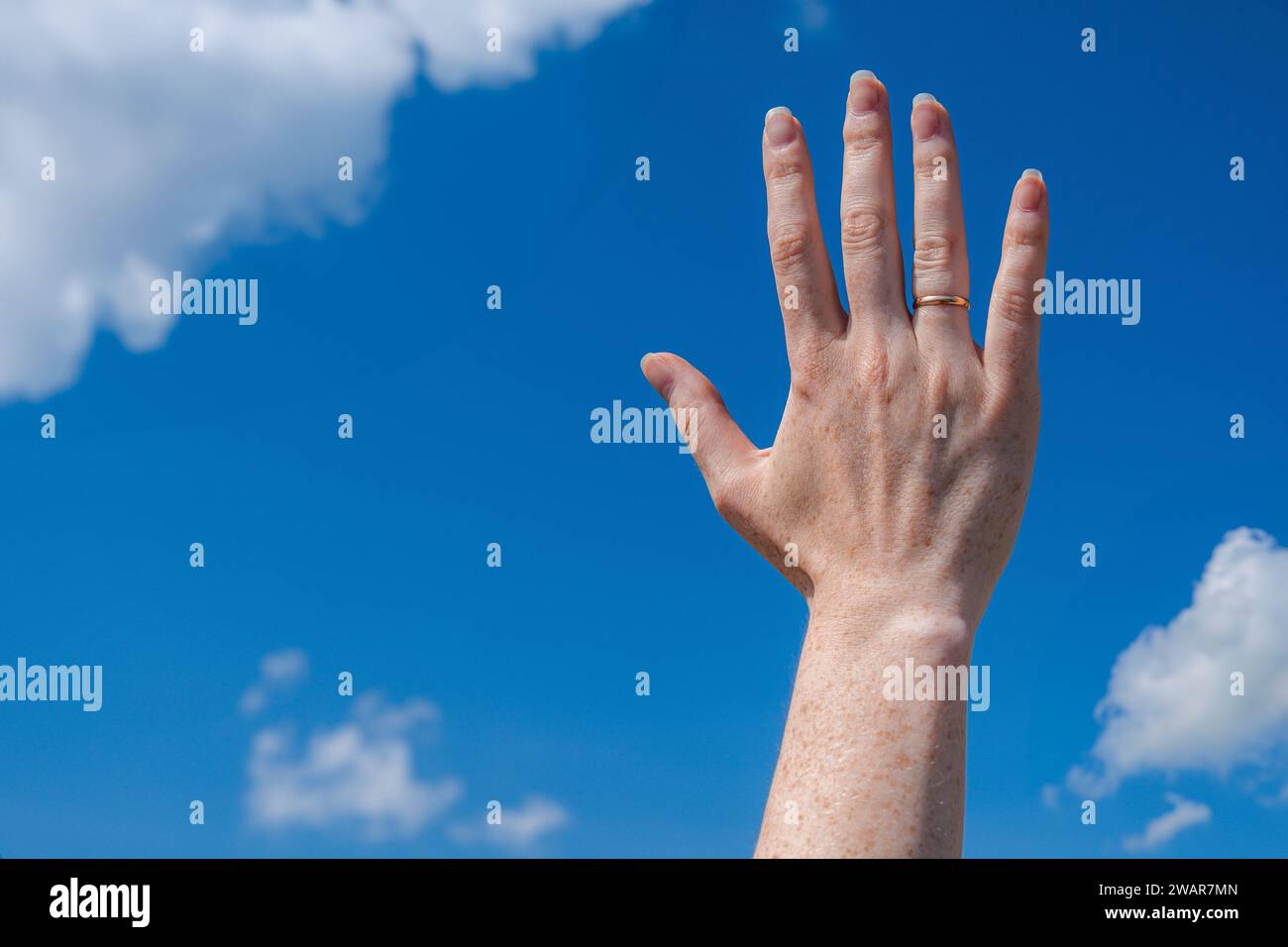beautiful open hand with a ring. Sky background with clouds Stock Photo