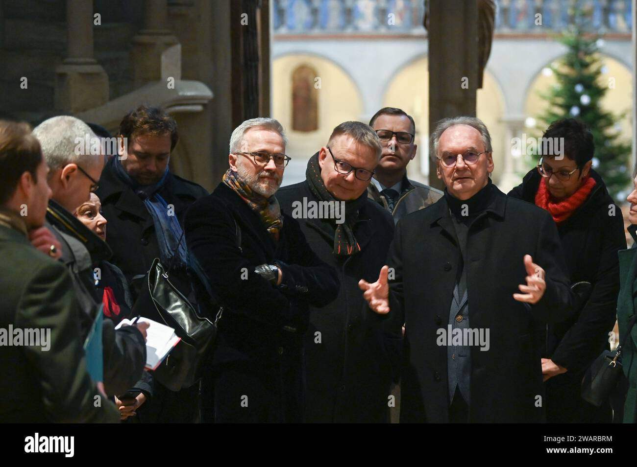 Naumburg, Germany. 06th Jan, 2024. Saxony-Anhalt Minister President Reiner Haseloff (2nd from left) during his visit to Naumburg Cathedral together with Foundation Director Holger Kunde and painter Michael Triegel. The reason for the visit is the return of the Cranach-Triegel Altarpiece. The altar has been reopened since the beginning of December 2023. The Leipzig painter Michael Triegel completed the altarpiece created by Lucas Cranach the Elder between 1517 and 1519, which was later partially destroyed, and added a central section. Credit: Heiko Rebsch/dpa/Alamy Live News Stock Photo