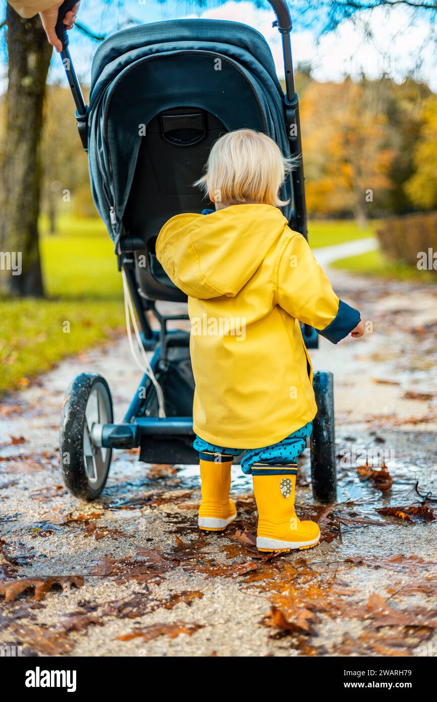 Baby boy wearing raincoat and life jacket while holding fishing