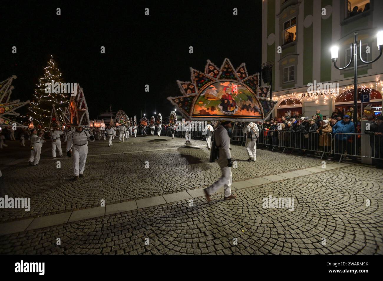 Dreikönigsingen und Glöcklerlauf am Rathausplatz in Gmunden, im oberösterreichischen Salzkammergut, am 05.01.2024. Sowohl das Dreikönigssingen als auch der Glöcklerlauf sind alte, eingeprägte Brauchtumsveranstaltungen im Salzkammergut in Österreich. Während des Glöcklerlaufs tragen junge Burschen prächtig geschmückte Laternenkappen mit meist lokalen Motiven am Kopf. Dabei wird durch laufen, springen und tanzen, mit an Gürteln der weiß Gekleideten angebrachten Glocken, entsprechend Lärm gemacht und dazu gesungen Damit treiben die Glöckler in der letzten Rauhnacht der Saison, dem 5.1. eines jede Stock Photo
