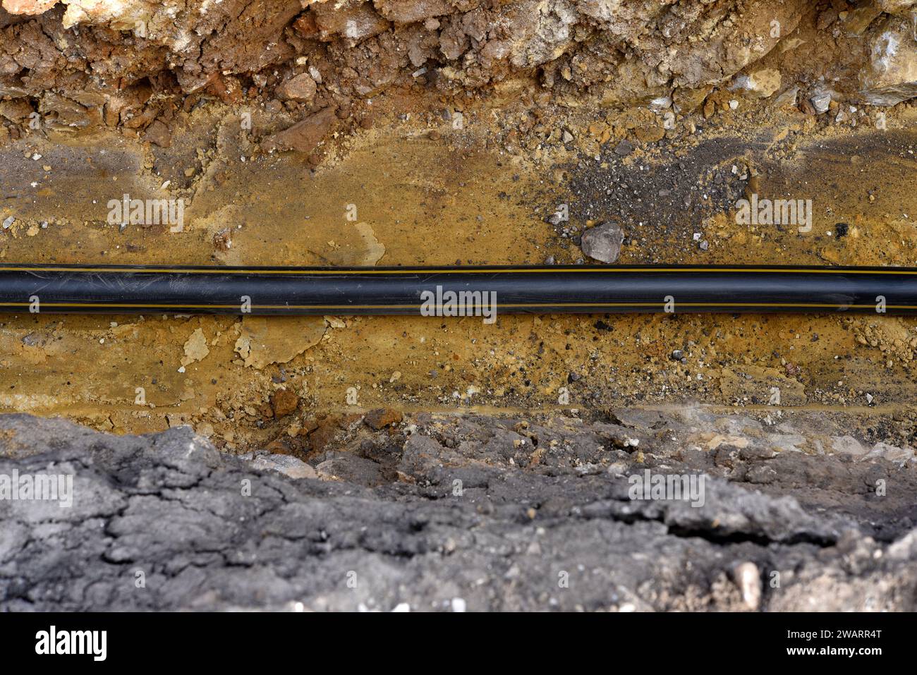 A plastic black gas pipe at the bottom of the trench. A dug trench for