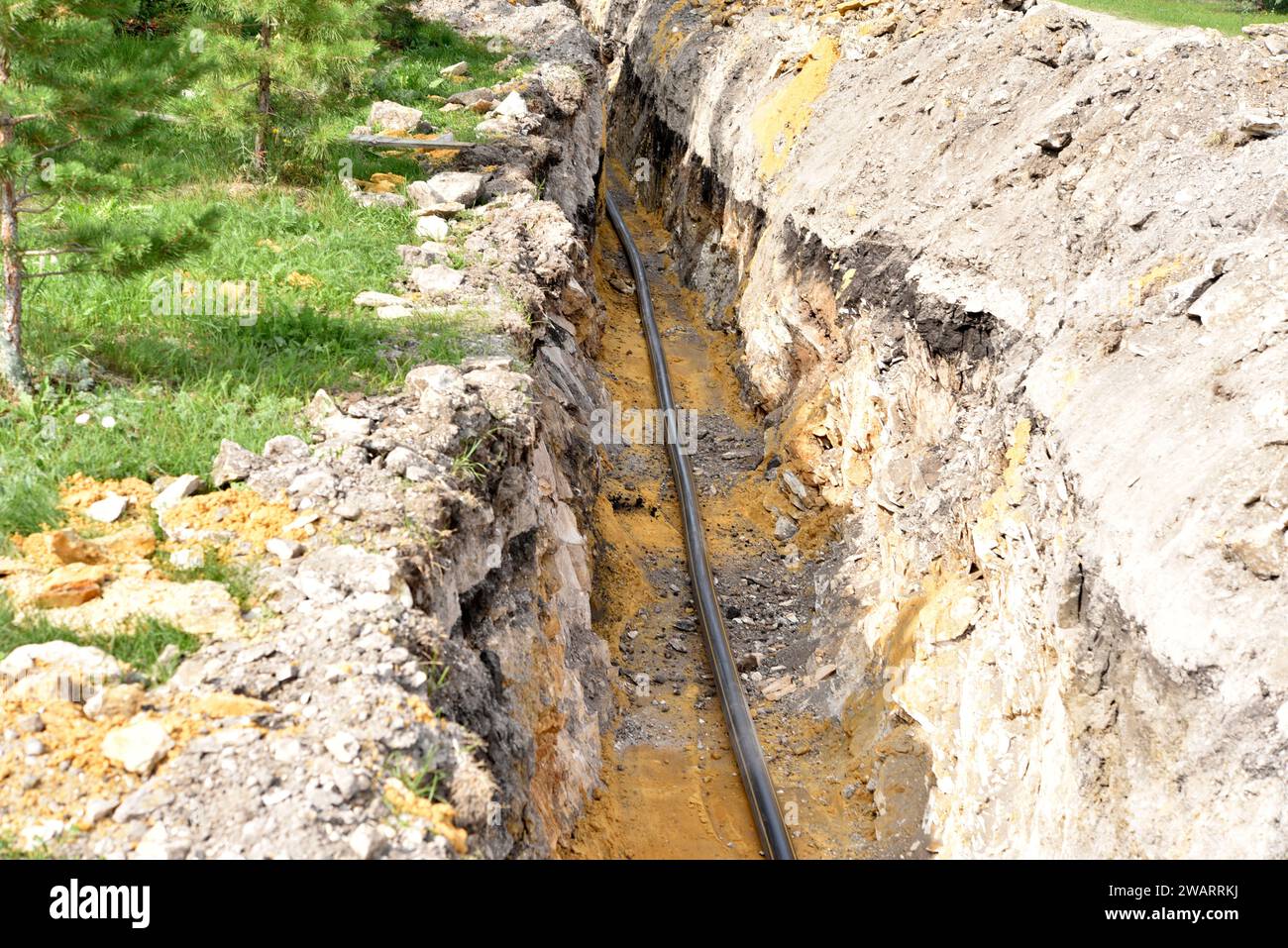 A plastic black gas pipe at the bottom of the trench. A dug trench for