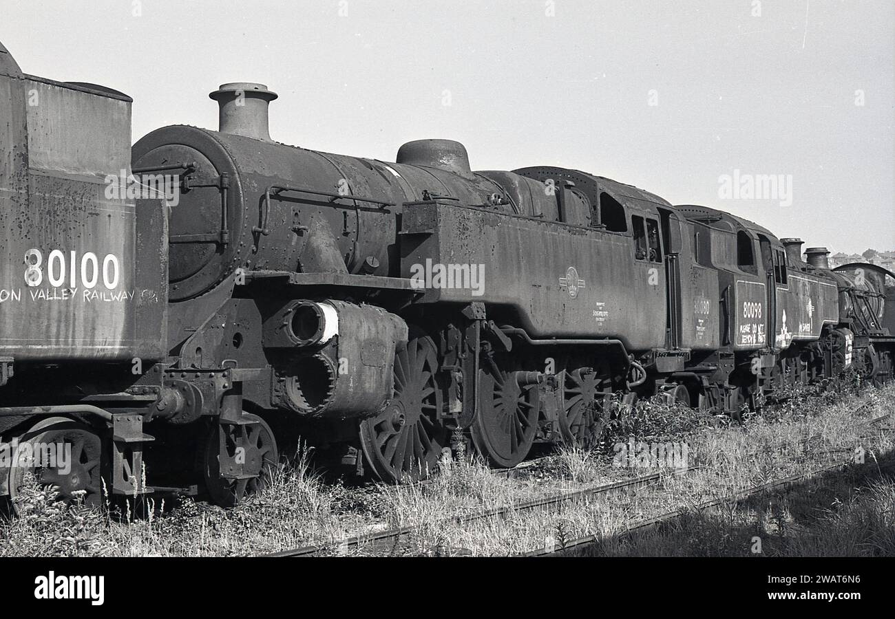 1975, historical, old steam locomotives at the Woodham Brothers scrapyard at Barry Docks, South Wales, commonly known as Barry Scrapyard. No 80100, is taken for Valley Railway, No 80080, Reserved for Steamport Southport Ltd, Carriage, no 80098, writing says, Do Not Remove, Paid. The Woodham Brothers, scrap metal merchants established in 1892, brought the old Briitsh Railways steam locomotives and then either sold them on or scrapped them. It is estimated that over 200 steam locomotives were sold and so rescued for the railway preservation movement. Stock Photo