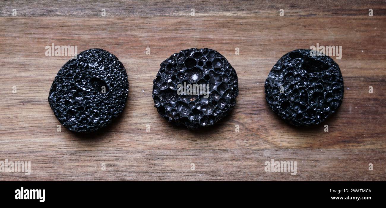 Black lava stones on the wooden background. Stock Photo