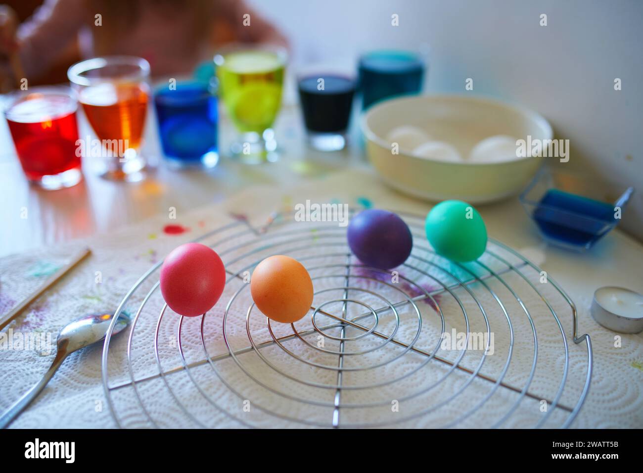 Using food coloring to dye Easter eggs at home. Painting colorful eggs for Easter hunt. Getting ready for Easter celebration. Family traditions. Stock Photo