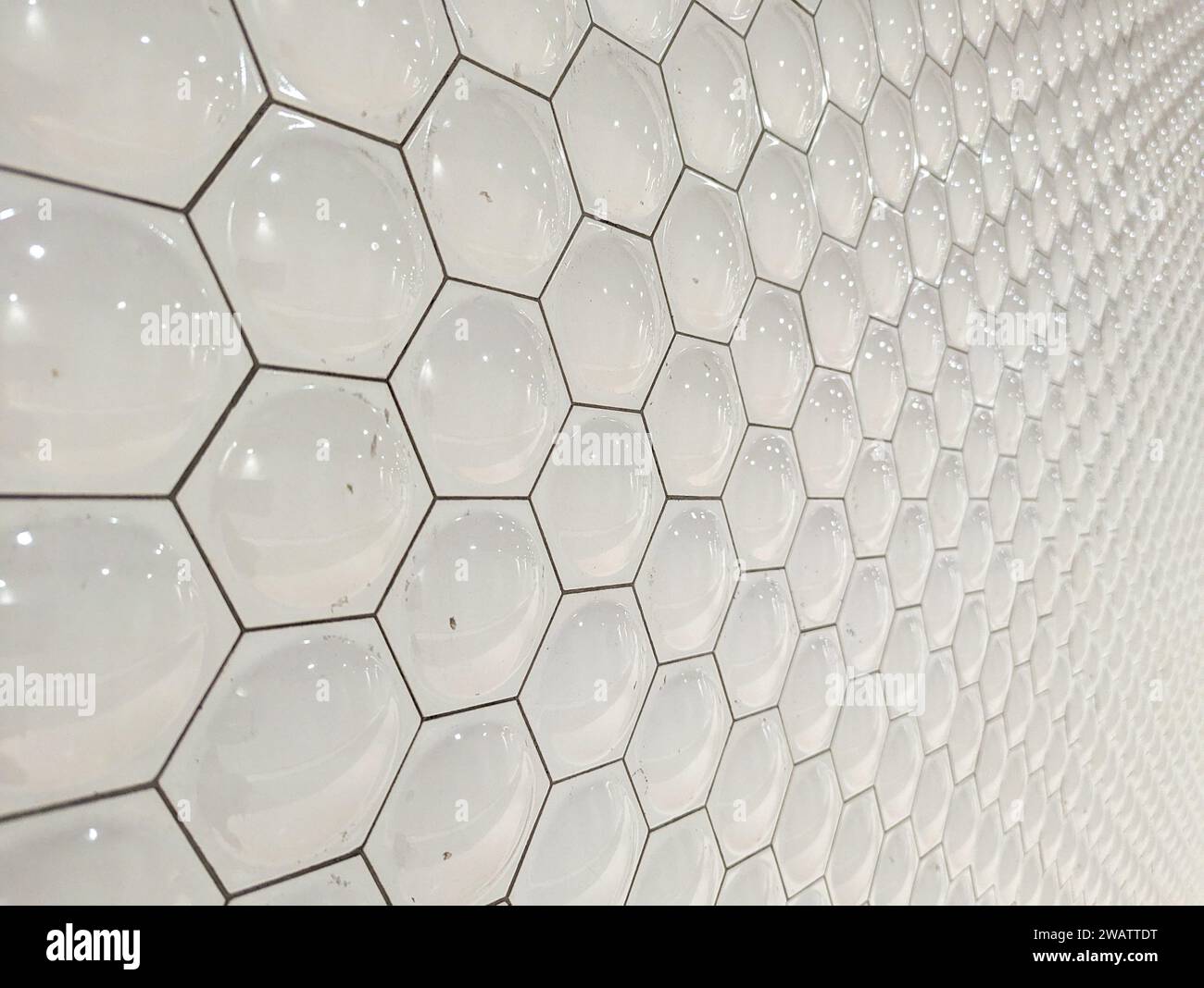 A wall tiled in white hexagons Stock Photo
