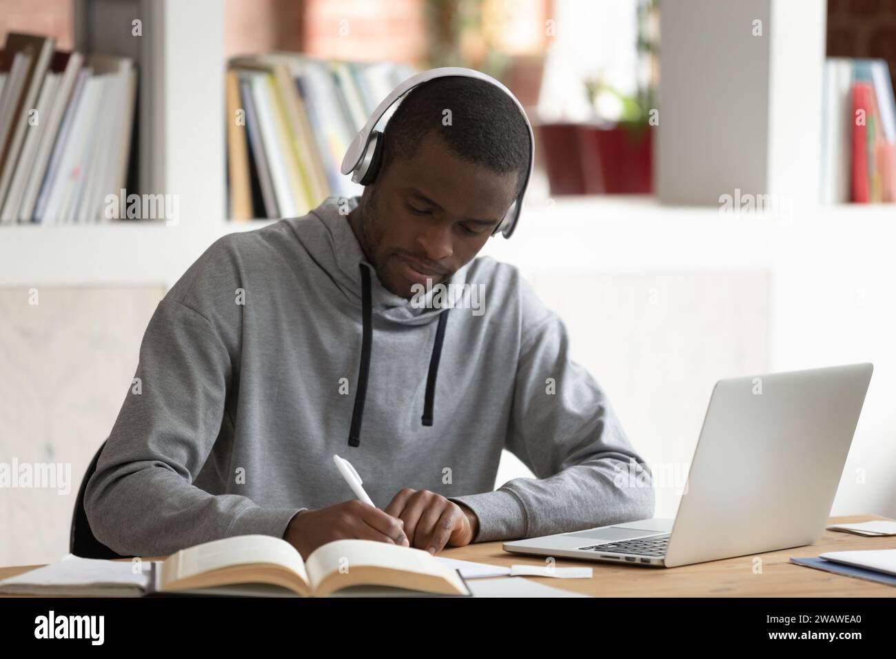 Focused biracial guy writing studying using laptop Stock Photo