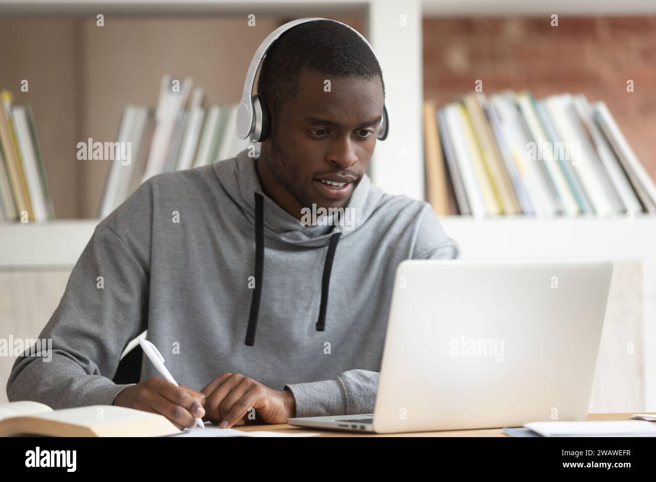Focused biracial guy make notes watching educational webinar Stock Photo