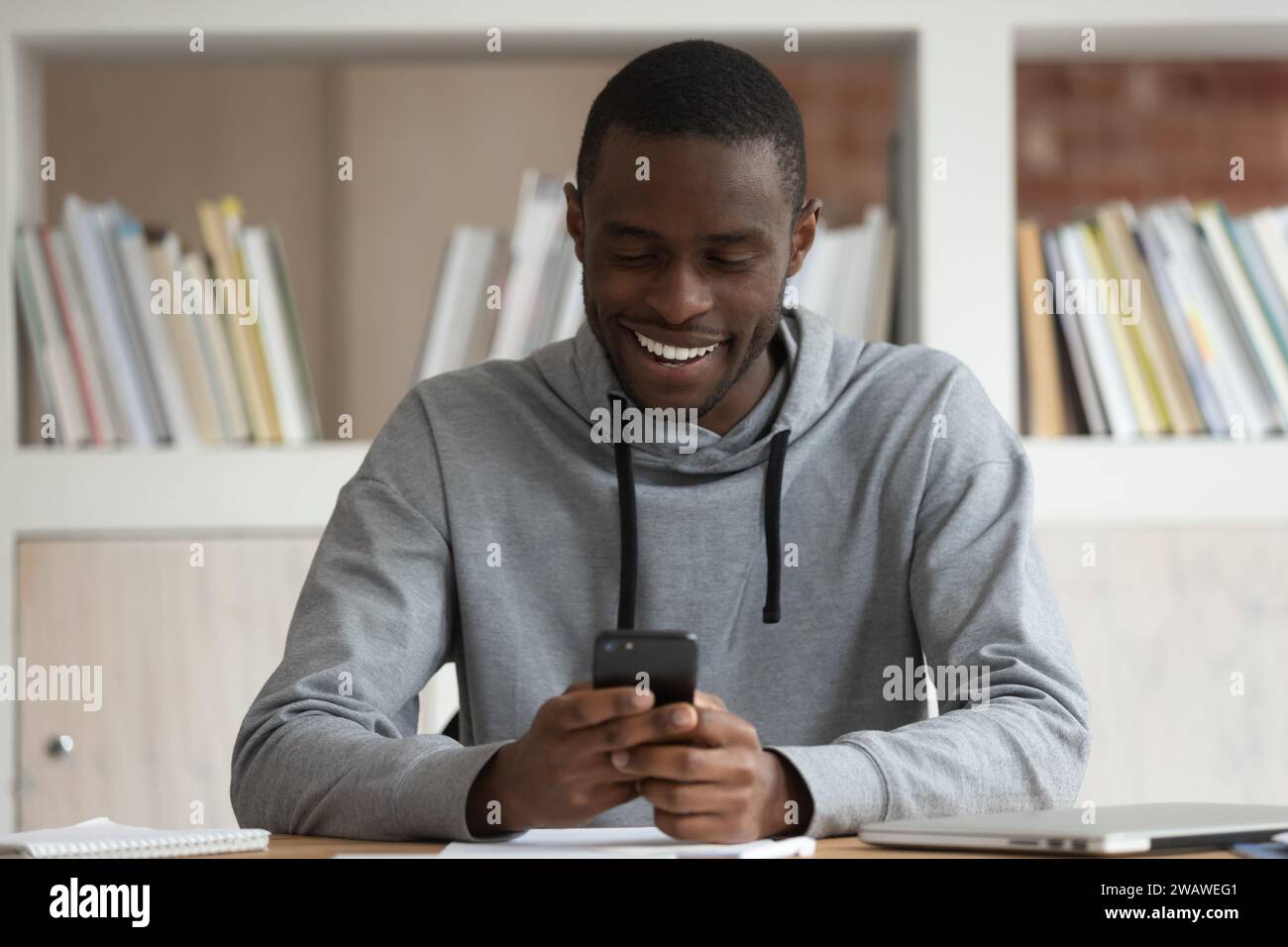 Smiling biracial male student have fun using smartphone Stock Photo