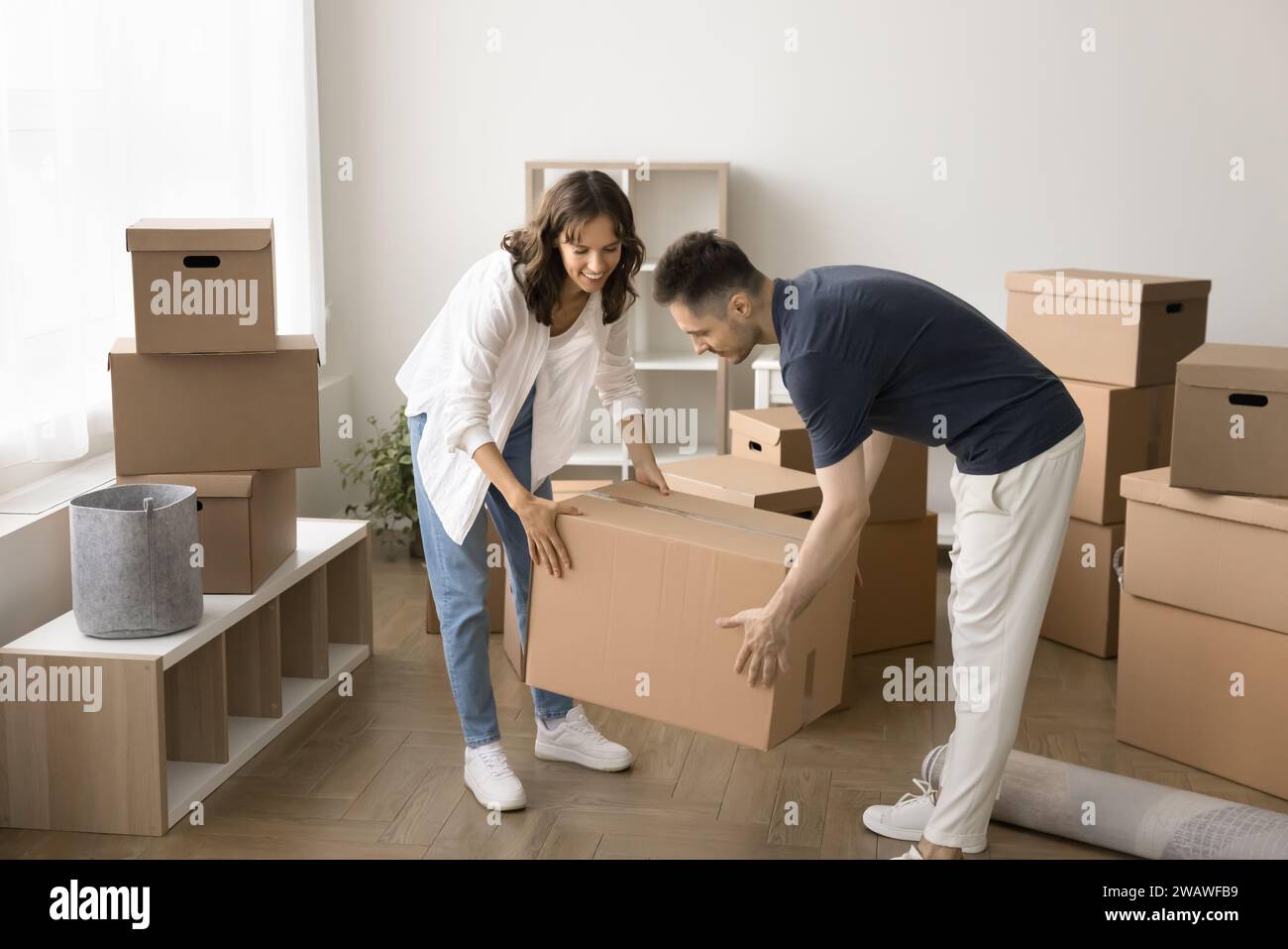 Happy busy couple of home owners unpacking cardboard boxes Stock Photo