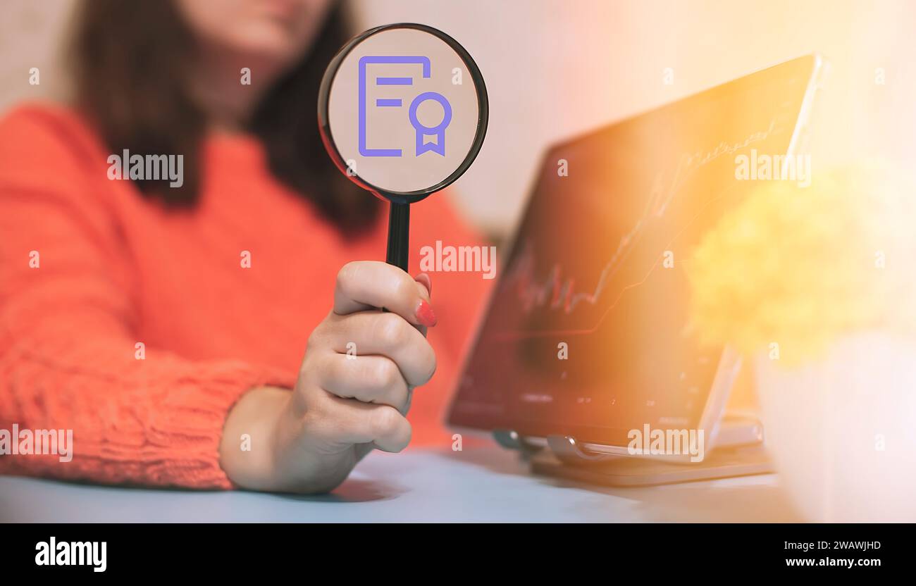 Woman holding a magnifying glass with a financial literacy certificate Stock Photo