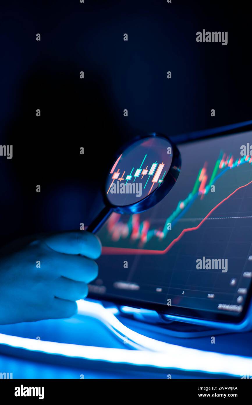 Businessman analyzes investment charts using a magnifying glass