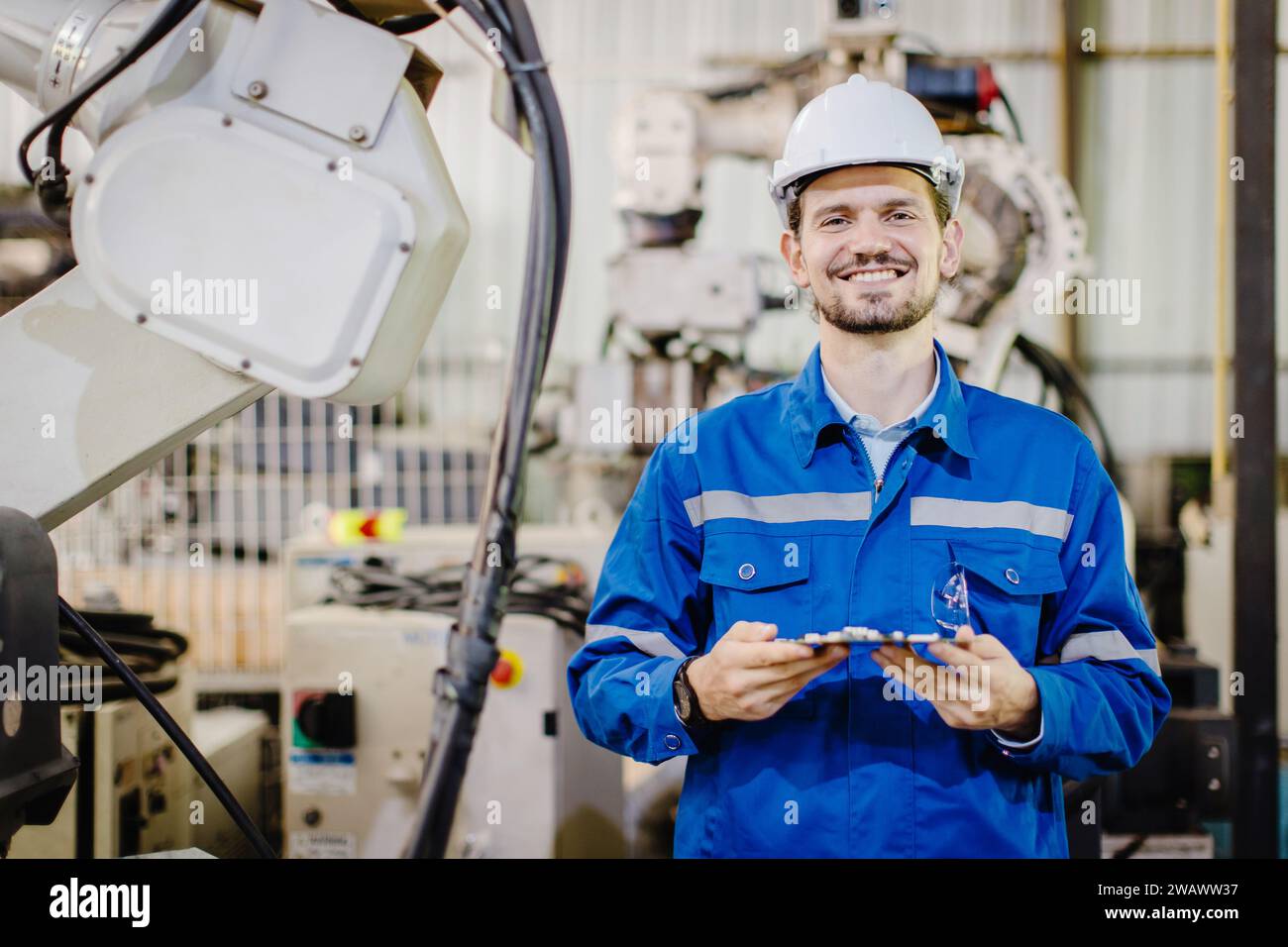 portrait happy smiling engineer service staff worker in robotic workshop robot arm plant assembly industry. Stock Photo