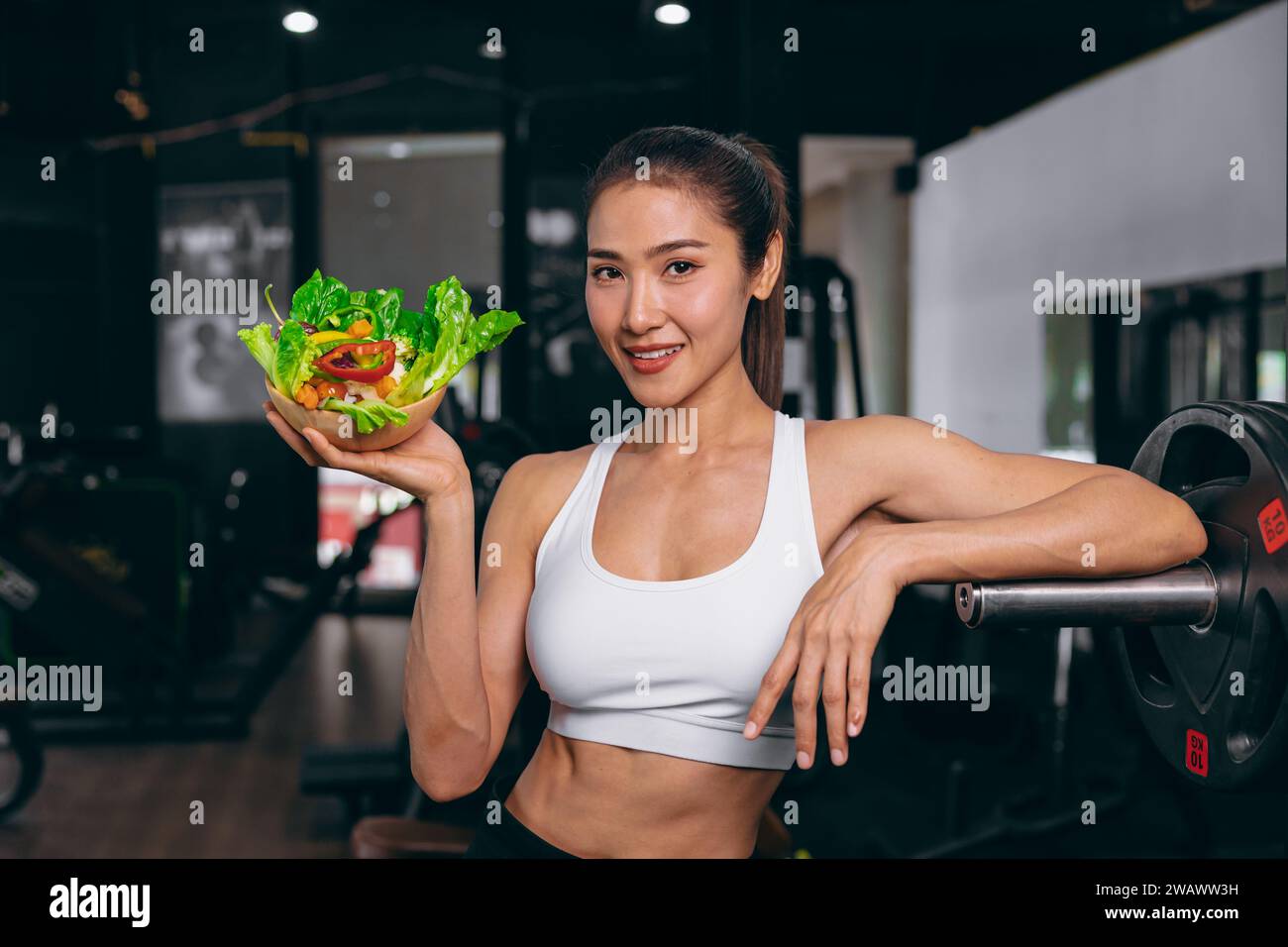 sport healthy beautiful asian woman showing vegetables mix salad for diet food low calories in fitness sport club Stock Photo