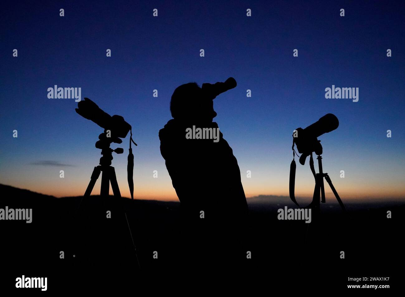 A man scours the night sky with binoculars and camera equipment from the Rock of Dunamase in Co Laois. The UK has been urged to follow the US and take UFO reports more seriously. There has been a significant fall in the number of sightings reported to police in Northern Ireland in the last year. Picture date: Saturday January 6, 2024. Stock Photo