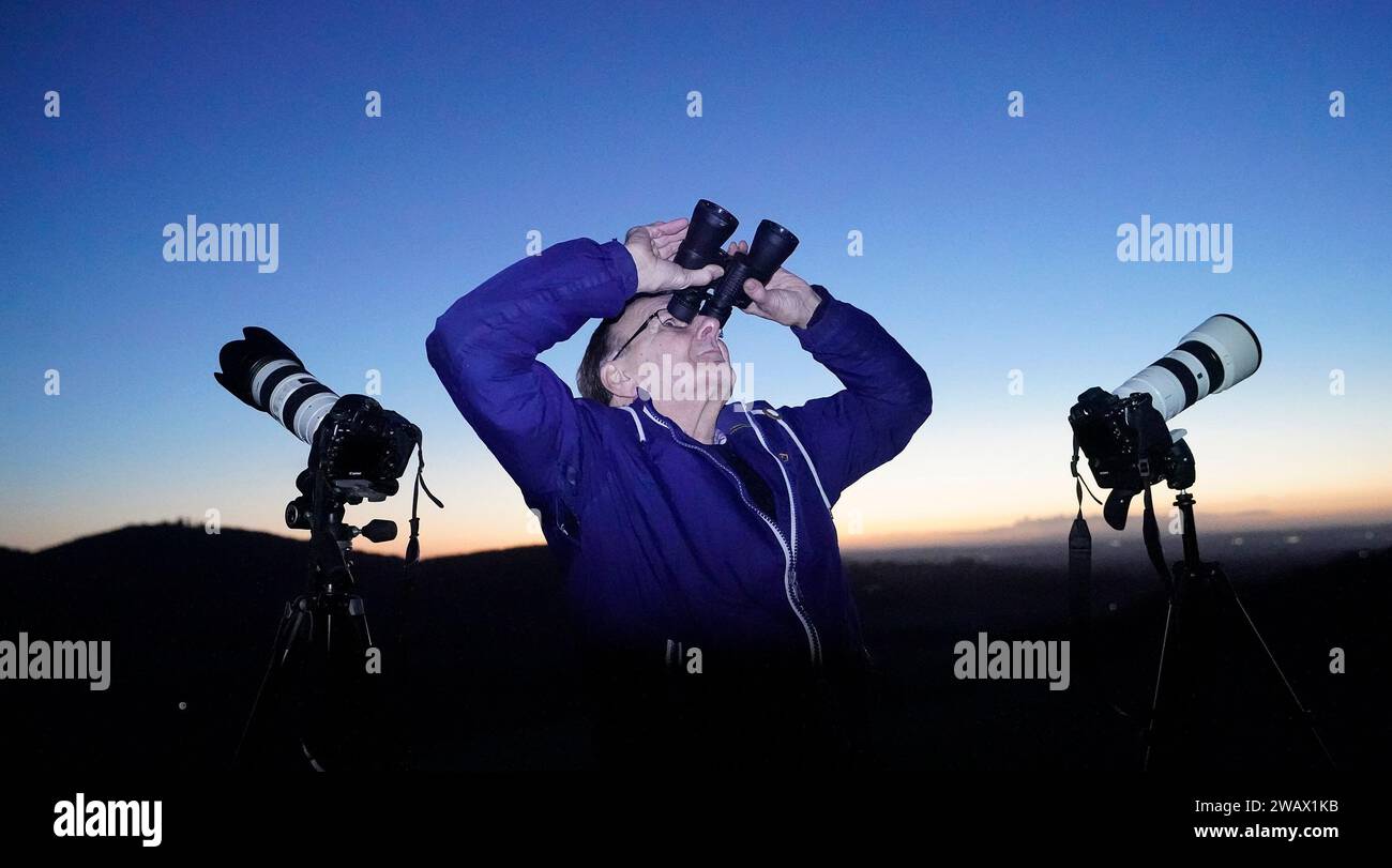 A man scours the night sky with binoculars and camera equipment from the Rock of Dunamase in Co Laois. The UK has been urged to follow the US and take UFO reports more seriously. There has been a significant fall in the number of sightings reported to police in Northern Ireland in the last year. Picture date: Saturday January 6, 2024. Stock Photo