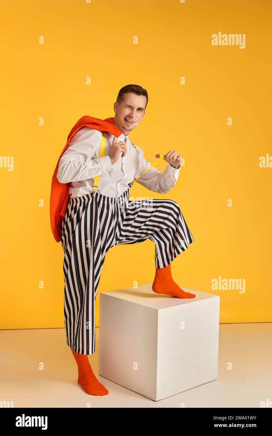 funny crazy guy in orange jacket and striped pants pull his suspenders