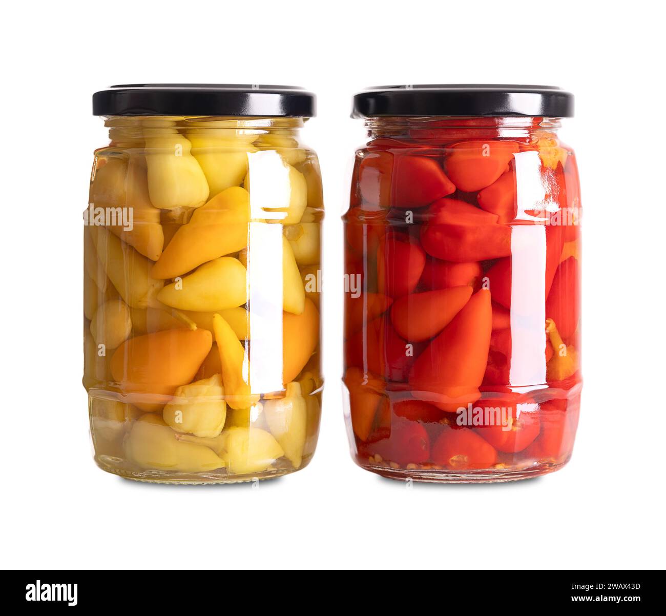 Yellow and red hot baby peppers pickled in glass jars. Two glasses with small hot chilis or pepperonis, pasteurized and preserved in a brine. Stock Photo