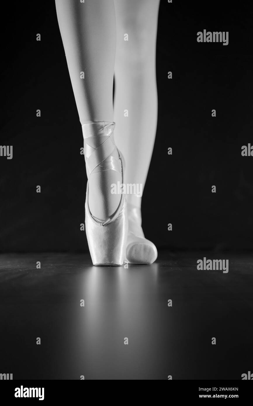 detail of female ballet dancer's feet in ballet position with pointe shoe in front of dark background Stock Photo
