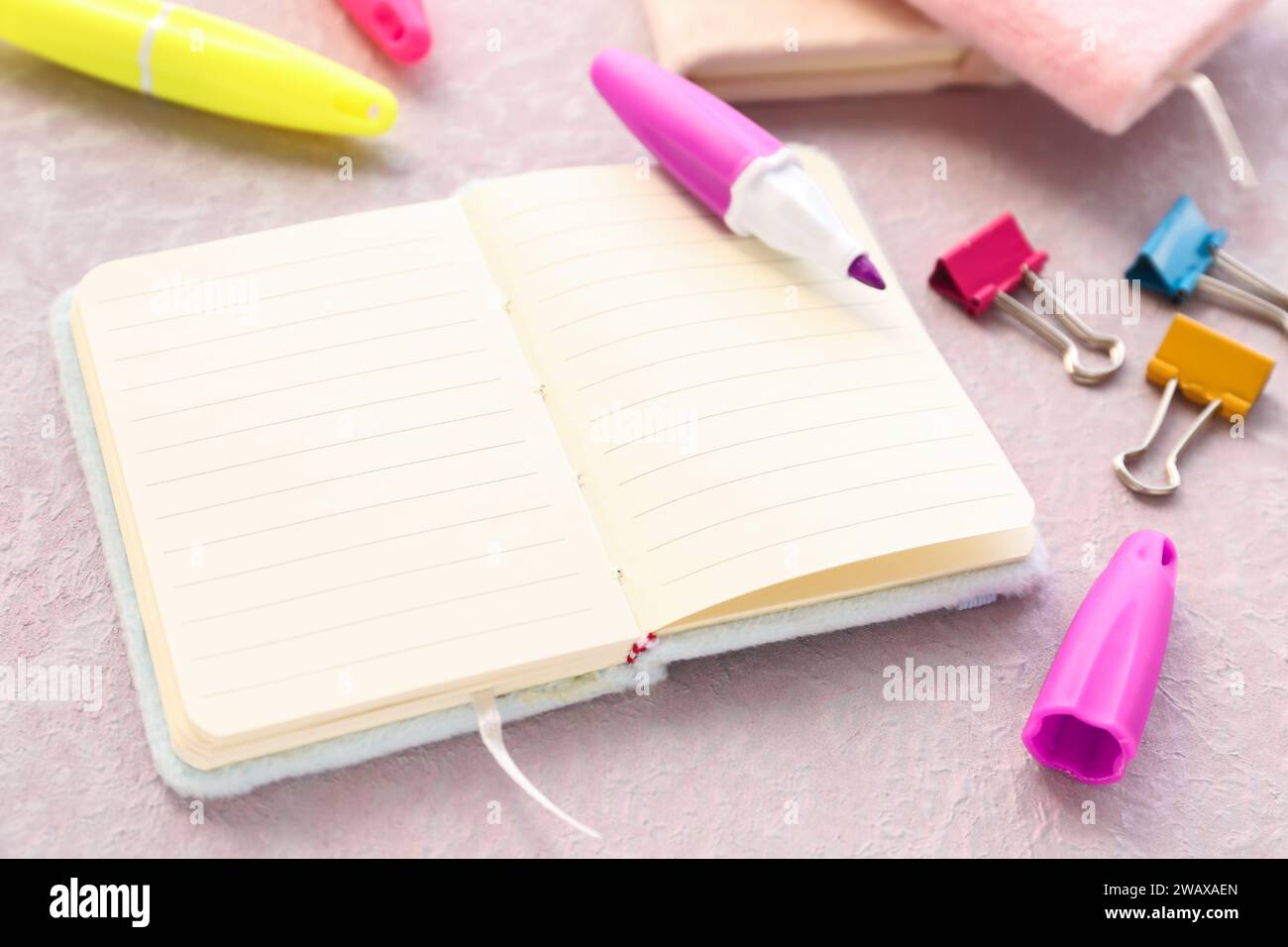 Blank open notebook, markers and binder clips on light background, closeup Stock Photo