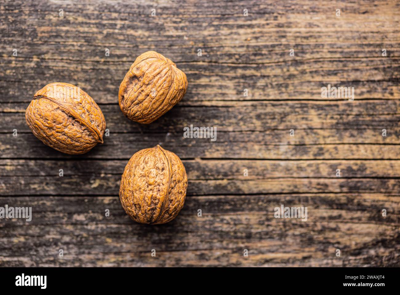 Three walnuts on the wooden table. Top view. Stock Photo