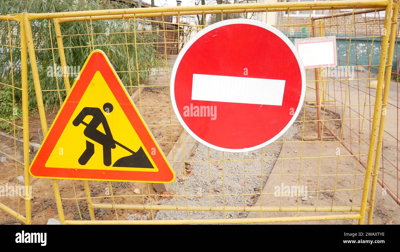 Stop and road works signs on a fence, construction and building ...