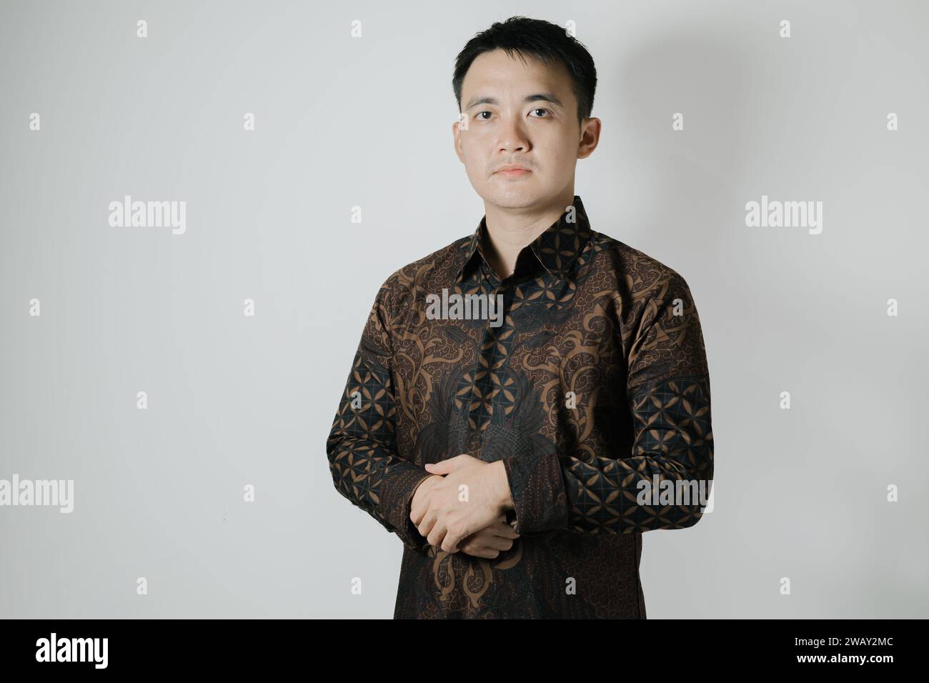 The portrait of Asian man wearing Indonesian traditional Batik cloth on white background Stock Photo